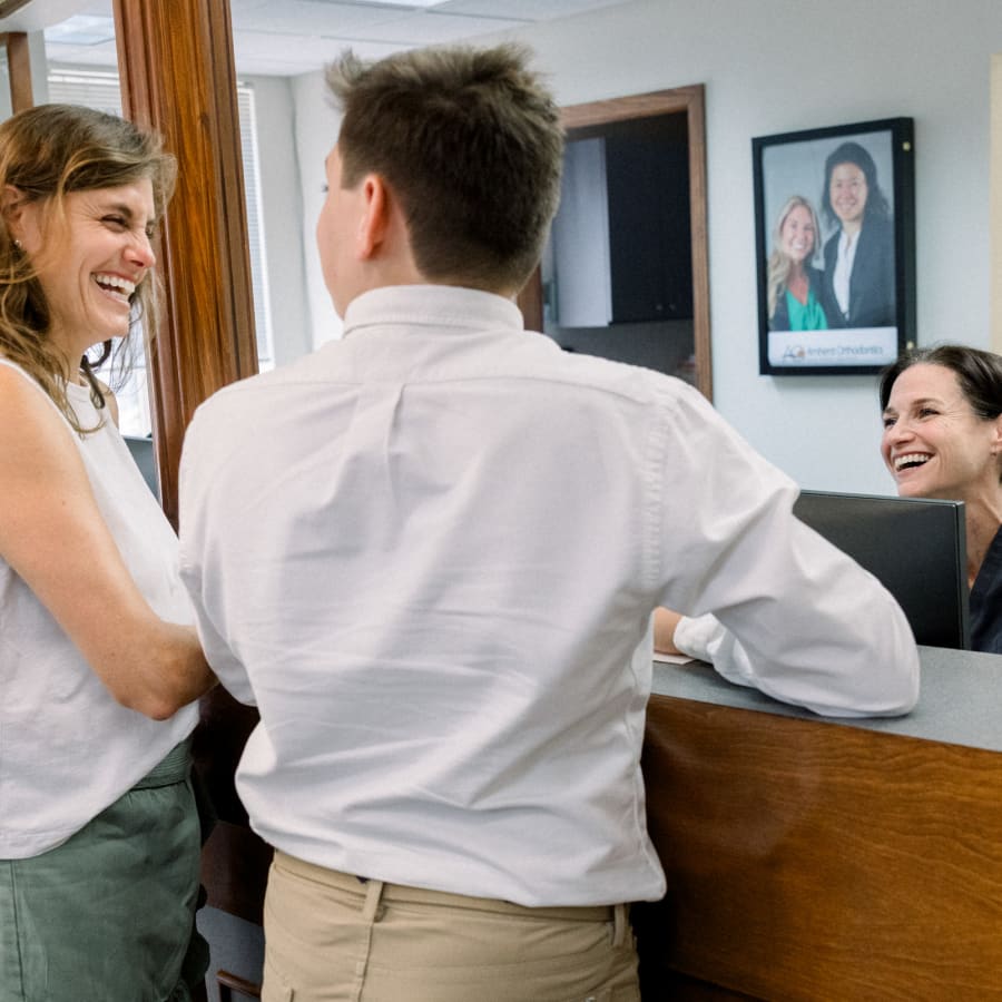 A woman and her son are at the reception counter at All Star Smiles Orthodontics