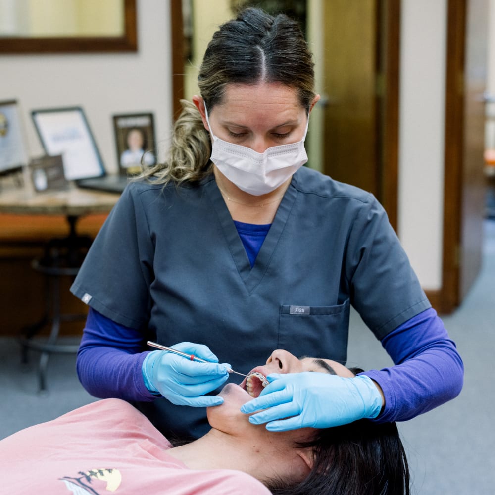 An orthodontist is working on a patient's braces.