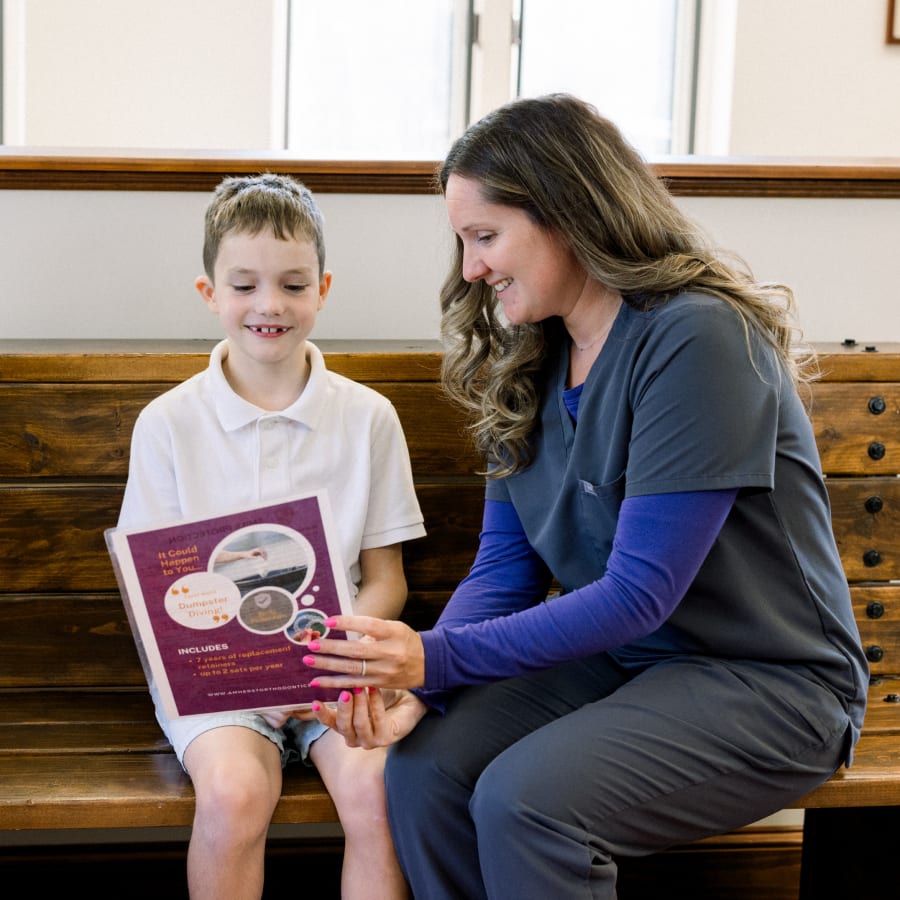 An orthodontic professional shows a child a poster.