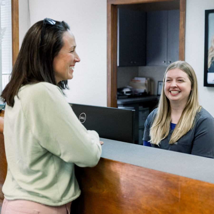 A woman and a receptionist are chatting over the reception table.