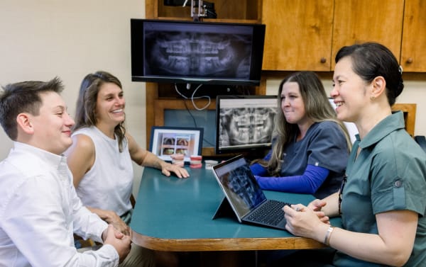 Dr. Diane is sitting with a patient and their parent at a table for a consultation.