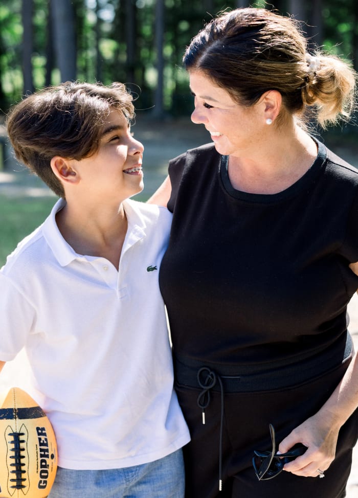 A mom is smiling and looking at her son. He is smiling at her, revealing braces.