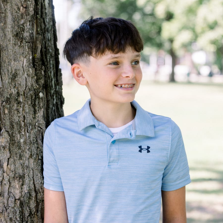 A young boy in a blue shirt smiles, showing off his braces.
