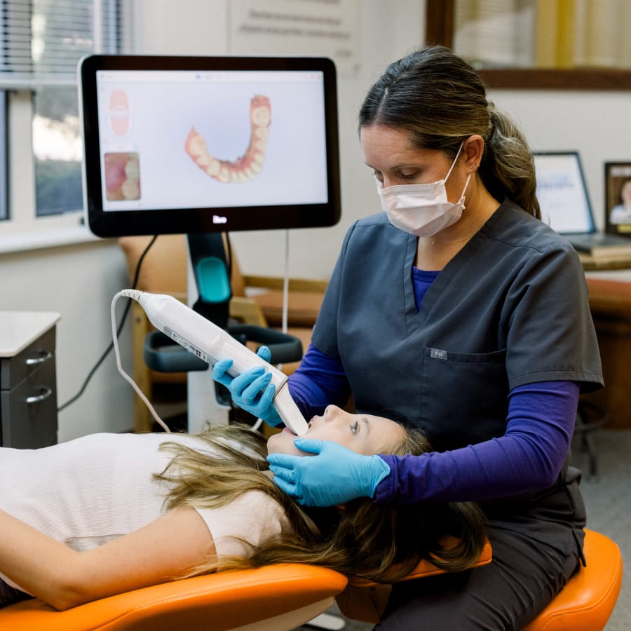 An orthodontist uses an iTero scanner on a young patient's mouth to create a 3D rendering.